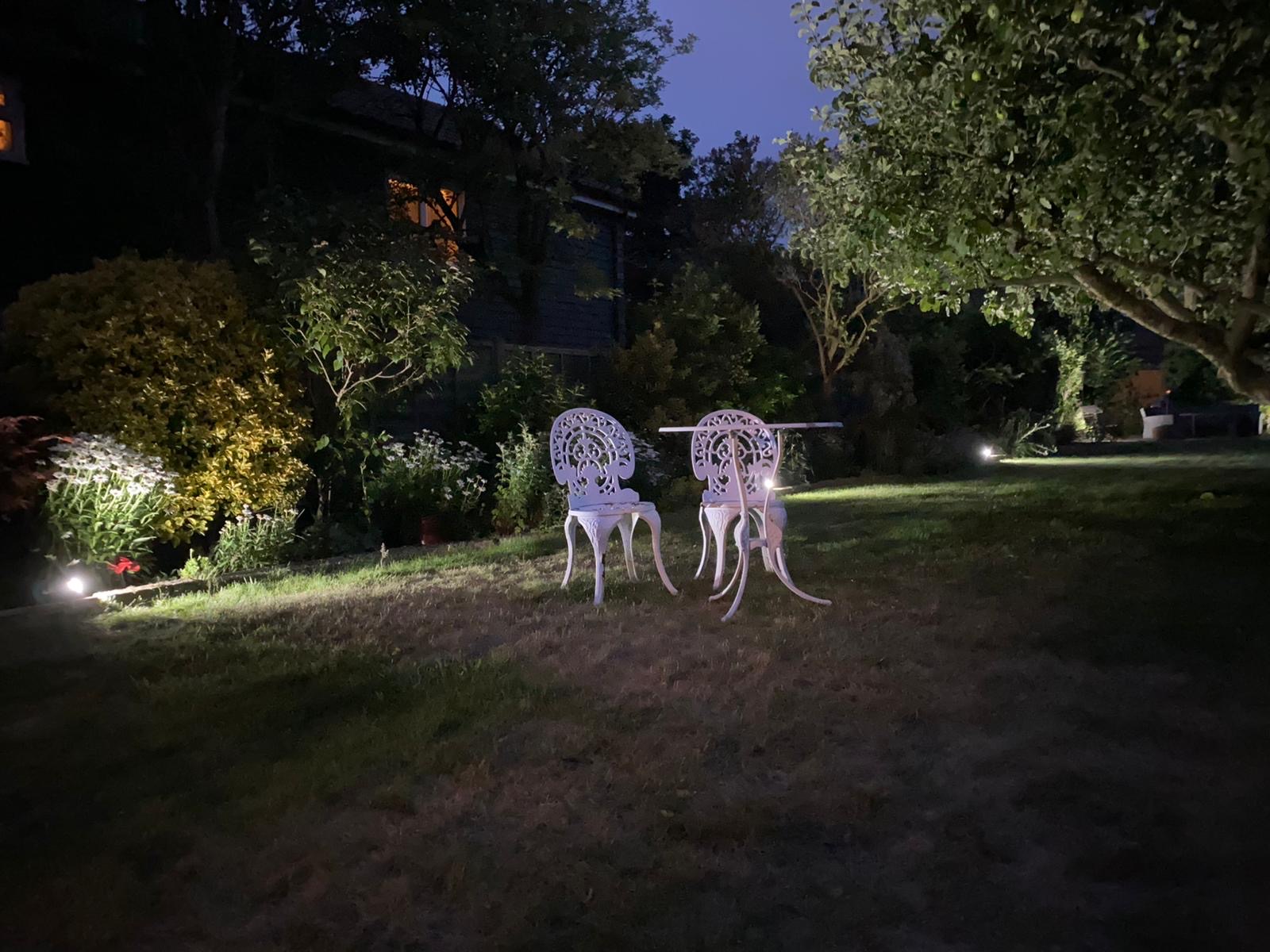 Garden lighting illuminating patio furniture and trees at dusk